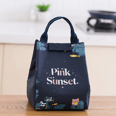 Navy blue tote bag with 'Pink Sunset' text and illustrations on a wooden surface.